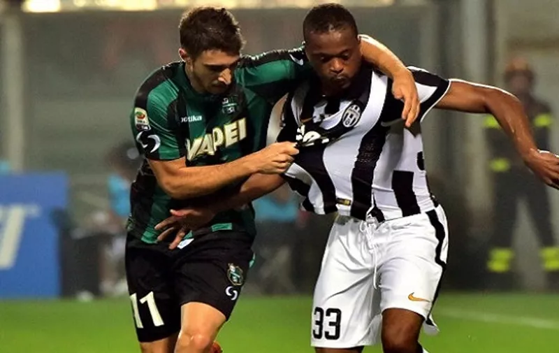 Juventus French midfielder Patrice Evra (R) fights for the ball with Sassuolo's Croatian defender Sime Vrsaljko during the Serie A football match between Sassuolo and Juventus at the Mapei Stadium in Reggio Emilia on October 18, 2014. AFP PHOTO / GIUSEPPE CACACE