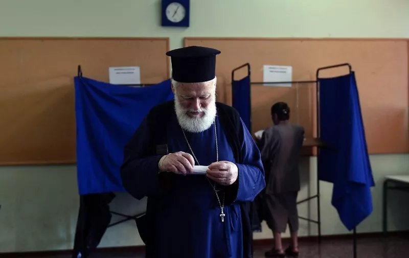 An Orthodox priest prepares to cast his ballot for the Greek referendum at a polling station in Athens on July  5, 2015. Nearly 10 million Greek voters headed to the polls today to vote in a historic, tightly fought referendum on whether to accept worsening austerity in exchange for more bailout funds, in a gamble that could see it crash out of the euro.  AFP PHOTO / LOUISA GOULIAMAKI