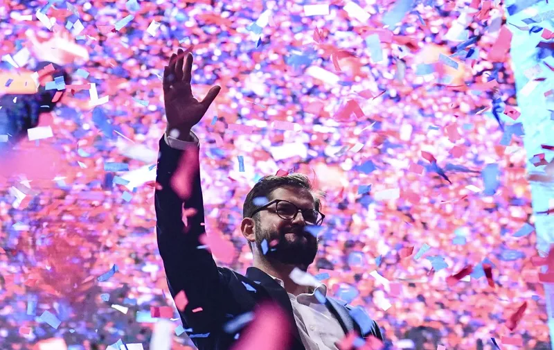 Chilean president-elect Gabriel Boric waves at supporters after delivering a speech, in Santiago, on December 19, 2021. - The streets of Santiago exploded in celebration Sunday after leftist millennial Gabriel Boric was declared Chile's new president with an unexpectedly large victory over his far-right rival in a polarizing race. Boric, 35, garnered nearly 56 percent of the vote compared to 44 percent for ultra-conservative Jose Antonio Kast, who congratulated the "president-elect" on Twitter even before the final result was known. (Photo by MARTIN BERNETTI / AFP)