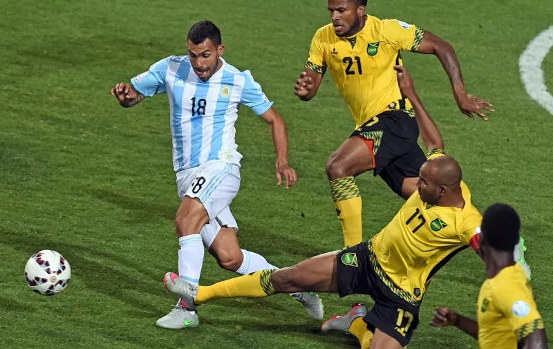 Argentina's forward Carlos Tevez (L) vies for the ball with Jamaica's defender Jermaine Taylor (C) and Jamaica's midfielder Rodolph Austin during their 2015 Copa America football championship match, in Vina del Mar, on June 20, 2015.      AFP PHOTO / PABLO PORCIUNCULA
