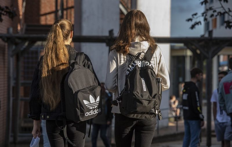 A student (L) carries a face mask as she heads into the Christophorusschule school in Rostock on August 3, 2020, as school resumed after the summer break in the German state of Mecklenburg-Vorpommern, amid a Coronavirus Covid-19 pandemic (Photo by John MACDOUGALL / AFP)