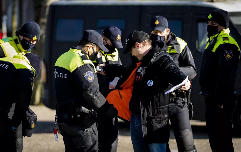 A man is being checked by police officers on the Museumplein in Amsterdam on January 31, 2021 as Nederland in Verzet action group called for a protest against the Covid-19 guidelines. (Photo by STRINGER / ANP / AFP) / Netherlands OUT