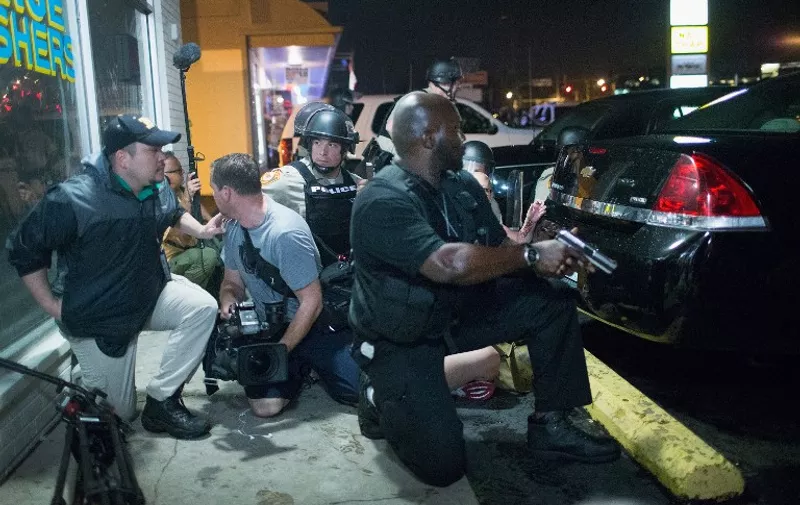 FERGUSON, MO - AUGUST 09: Police take cover as a barrage of gunfire erupts along West Florrisant Street during a demonstration to mark the one-year anniversary of the shooting of Michael Brown on August 9, 2015 in Ferguson, Missouri. Brown was shot and killed by a Ferguson police officer on August 9, 2014. His death sparked months of sometimes violent protests in Ferguson and drew nationwide focus on police treatment of black offenders.   Scott Olson/Getty Images/AFP