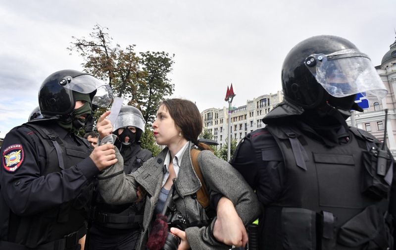 Riot police officers detain a journalist during an unsanctioned rally urging fair elections at Moscow's Pushkinskaya Square on August 3, 2019. - The rally is the latest in a series of demonstrations after officials refused to let popular opposition candidates run in next month's city parliament elections. (Photo by Alexander NEMENOV / AFP)