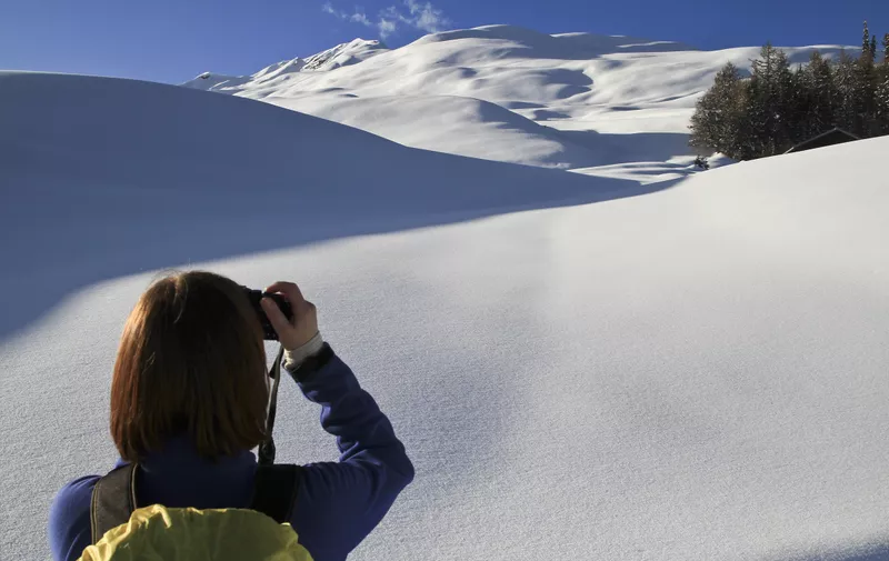 Switzerland --- Tourist takes photos of snowy landscape --- Image by © Gerhard Fitzthum/fstop/Corbis