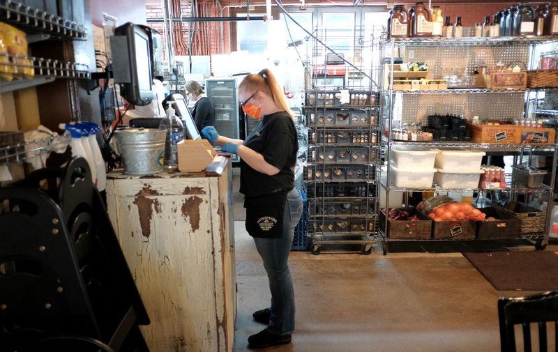 NASHVILLE, TENNESSEE - APRIL 27: A waitress wearing rubber gloves and a mask is seen taking orders for patrons at Puckett's Grocery &amp; Restaurant on April 27, 2020 in Franklin, Tennessee. Tennessee is one of the first states to reopen restaurants after the onset of the coronavirus (COVID-19). Restaurants are allowed to open at 50% capacity and maintain social distancing.   Jason Kempin/Getty Images/AFP