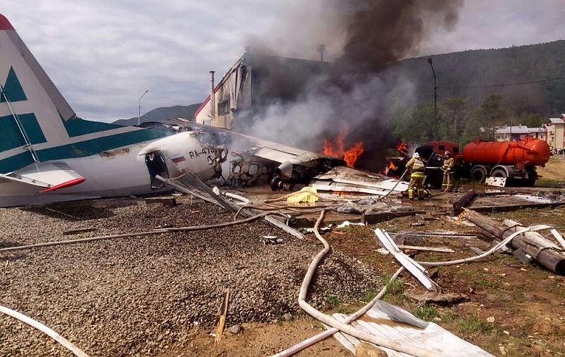 In this handout picture released by the Russian Emergency Situations Ministry on June 27, 2019, firefighters work on extinguishing a fire on an An-24 passenger plane after its emergency landing at Nizhneangarsk airport. - A Russian passenger plane overshot the runway, crashed into a building and caught fire at an airport in Siberia on June 27, 2019, killing two crew members, officials said. (Photo by HO / RUSSIAN EMERGENCY SITUATIONS MINISTRY / AFP) / RESTRICTED TO EDITORIAL USE - MANDATORY CREDIT "AFP PHOTO / RUSSIAN EMERGENCY SITUATIONS MINISTRY / HO" - NO MARKETING NO ADVERTISING CAMPAIGNS - DISTRIBUTED AS A SERVICE TO CLIENTS