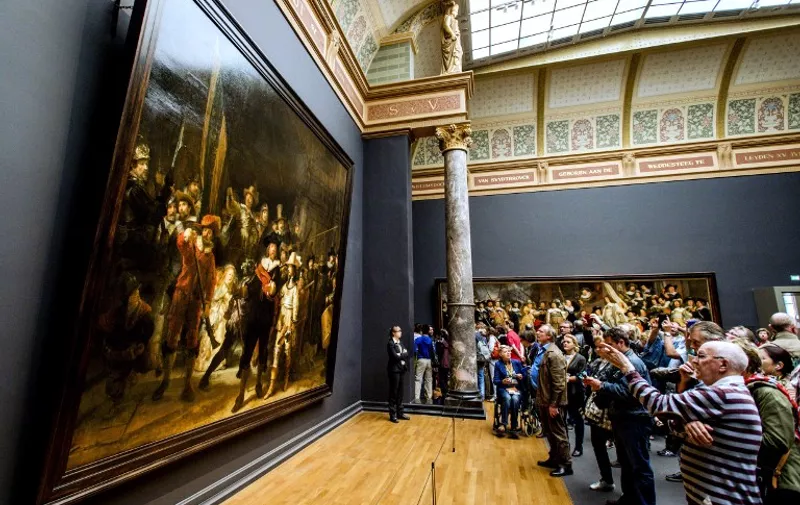 Visitors looks at Rembrandt's "The Night Watch" in the Rijksmuseum in Amsterdam, on May 17, 2015. The Dutch Rijksmuseum museum was awarded the 2015 European Museum of the Year Award (EMYA) on May 16. The world-famous museum was closed for almost a decade to allow for a complete overhaul of the building, which enabled the creation of new concourse spaces, better visitor services and circulation. AFP PHOTO / ANP / ROBIN VAN LONKHUIJSEN   **NETHERLANDS OUT** / AFP / ANP / ROBIN VAN LONKHUIJSEN