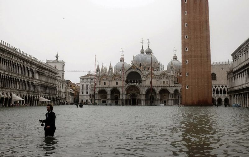 A man walks in the flooded St. Mark's Square during a high-water (Acqua Alta) alert in Venice on October 29, 2018 - The flooding, caused by a convergence of high tides and a strong Sirocco wind, reached around 150 centimetres on October 29. (Photo by MIGUEL MEDINA / AFP)
