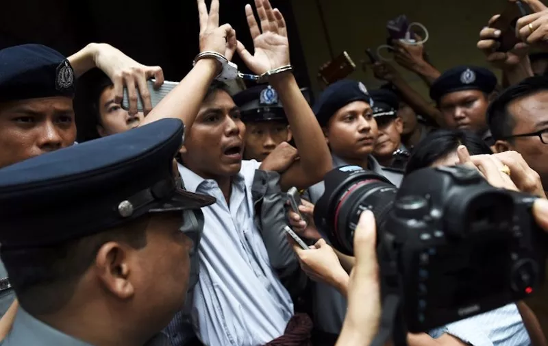 (FILES) This file photo taken on September 03, 2018 shows Myanmar journalist Kyaw Soe Oo (C) is escorted by police after being sentenced by a court to jail in Yangon. - Two Reuters journalists jailed in Myanmar over their investigation of atrocities committed against the Rohingya will learn January 11 if an appeal against their conviction has succeeded. (Photo by Ye Aung THU / AFP)
