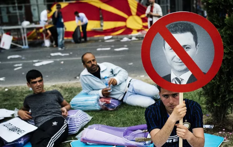 A protestor holds a placard with a picture of the Macedonian Prime Minister Nikola Gruevski during an anti-government protest in downtown Skopje on May 17, 2015. More than 20,000 people rallied in Macedonia's capital to demand the resignation of Prime Minister Nikola Gruevski's government which is grappling with a deep political crisis and an outbreak of violence. AFP PHOTO / DIMITAR DILKOFF
