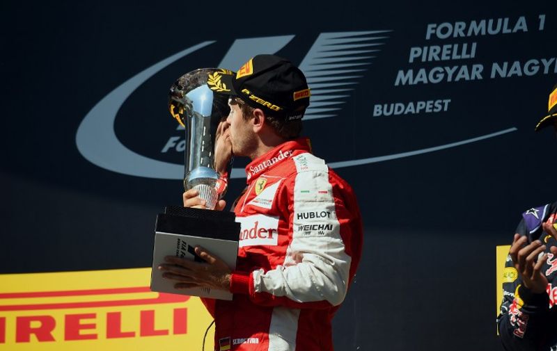 Ferrari's German driver Sebastian Vettel kisses the trophy as he celebrates on the podium winning the Hungarian Formula One Grand Prix at the Hungaroring circuit  near Budapest on July 26, 2015. 
 AFP PHOTO / ATTILA KISBENEDEK