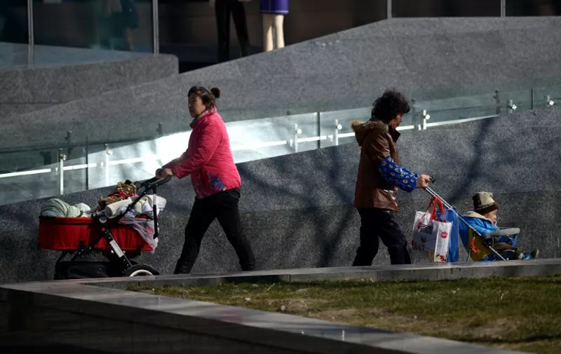 Two women push baby carriages as they walk along a road in Beijing on March 6, 2014.  China began to implement the loosening of its controversial one-child policy on January 17, when a province announced it has made it legal for couples to have two children if one parent is an only child.    AFP PHOTO / WANG ZHAO