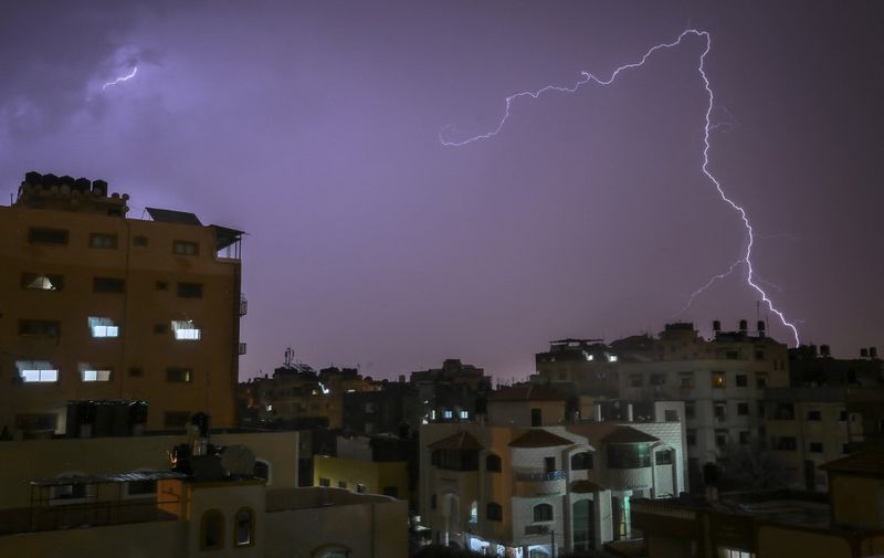 Lightning flashes over buildings during a thunderstorm in Gaza City on November 15, 2020. (Photo by MOHAMMED ABED / AFP)