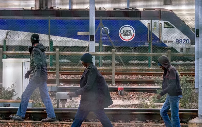 Migrants walk on the tracks in the Eurotunnel site in Frethun near Calais, northern France, on late July 30, 2015. French authorities said on July 30 that a migrant had died from head injuries suffered in a weekend attempt to cross the Channel into England, bringing the number of such deaths to 10 since June. Every night, hundreds of migrants make desperate attempts to enter the Eurotunnel premises in order to get to Britain, seen as an Eldorado. AFP PHOTO / PHILIPPE HUGUEN