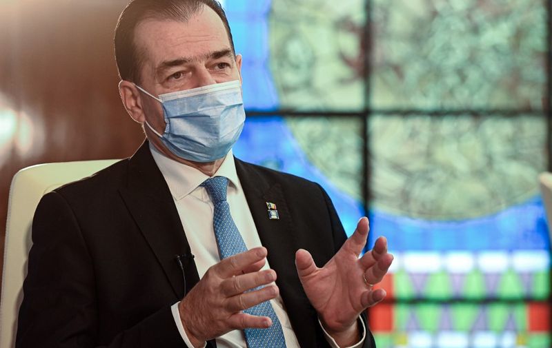 Romanian Prime Minister Ludovic Orban gestures as he gives an interview with AFP at The Victoria Palace, the Romanian Government headquarters, in Bucharest, November 19, 2020. - Orban said that the veto on the EU budget and coronavirus rescue plan exercised by Hungary and Poland is "negative for the whole EU". (Photo by Daniel MIHAILESCU / AFP)