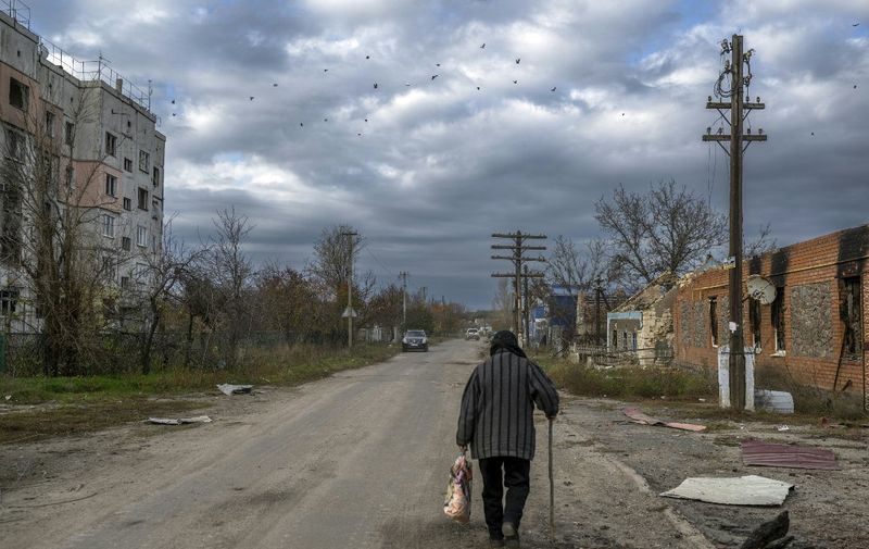 An old woman walks in the Kherson region village of Arkhanhelske on November 3, 2022, which was formerly occupied by Russian forces. (Photo by BULENT KILIC / AFP)