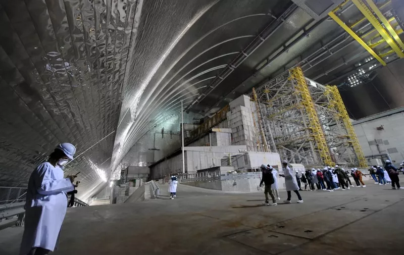 Visitors and journalists walk inside the New Safe Confinement (NSC) new metal dome designed and built by French consortium Novarka encasing the destroyed reactor at Chernobyl plant on July 10, 2019, in Chernobyl. - Ukraine and its European partners on July 10 formally inaugurated a new metal dome encasing the destroyed reactor at the infamous Chernobyl plant, wrapping up a two-decade effort. Branded as the world's largest moveable metal structure, the so-called New Safe Confinement seals the remains of the fourth reactor at the nuclear plant that was the site of the massive Chernobyl disaster in 1986. (Photo by SERGEI SUPINSKY / AFP)