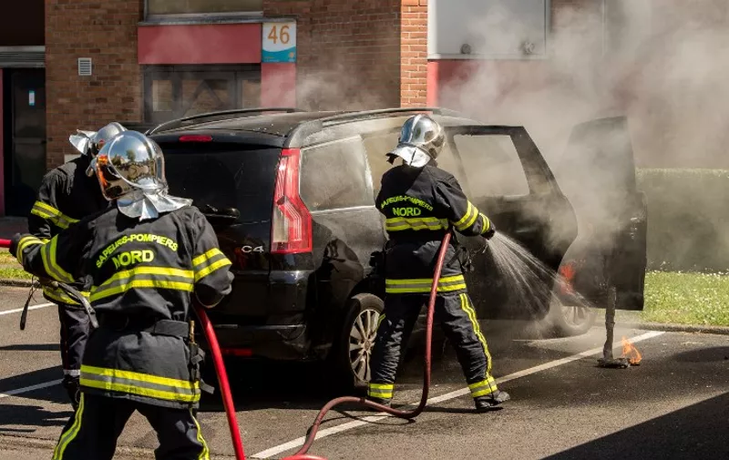 Firemen extinguish a burning car in the La Bourgogne neighborhood, in Tourcoing, northern France, on June 4, 2015, after a third night of violence which led to twenty arrests. Violences started on June 1, 2015 at night after a driver, who was trying to escape from a police control, crashed into a tree.  AFP PHOTO / PHILIPPE HUGUEN / AFP / PHILIPPE HUGUEN