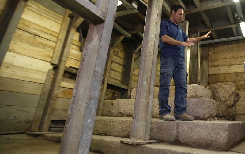 Israeli archaeologist Nahshon Szanton of the IAA (Israel Antiquities Authority) stands on top of a unique pyramid-shaped staircase structure exposed on the street ascending from the City of David, an archaeological site which lies just outside Dung Gate, immediately south of Jerusalems old city walls, on August 31, 2015. Israel Antiquities Authority believe the structure, which was constructed sometime in the fourth decade of the first century CE, was a kind of monumental podium that attracted the publics attention when walking on the citys main street. AFP PHOTO / GALI TIBBON