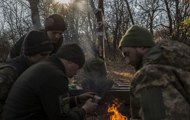 Ukrainian soldiers of an artillery unit have a rest near the bonfire outside Bakhmut on November 8, 2022, amid the Russian invasion of Ukraine. (Photo by BULENT KILIC / AFP)