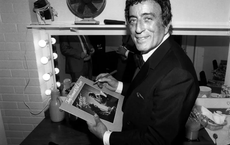 US singer Tony Bennett signs an autograph to a record in his loge on march 6, 1988 after the concert at the Stockholm "Börsen". (Photo by Bernt CLAESSON / PRESSENS BILD / AFP)
