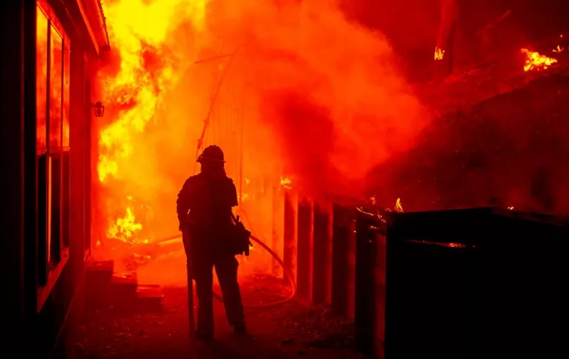 Firefighters attempt to save a burning house during the Valley fire in Seigler Springs, California on September 13, 2015. The governor of California declared a state of emergency Sunday as raging wildfires spread in the northern part of the drought-ridden US state, forcing thousands to flee the flames. The town of Middletown, population 1,300, was particularly devastated by the Valley Fire, according to local daily Santa Rosa Press-Democrat, which said the fire grew from 50 acres to 10,000 over just five hours Saturday -- before quadrupling in size overnight. AFP PHOTO/JOSH EDELSON