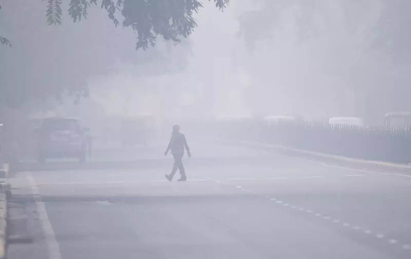 A man crosses a street in smoggy conditions in New Delhi on November 4, 2019. - Millions of people in India's capital started the week on November 4 choking through "eye-burning" smog, with schools closed, cars taken off the road and construction halted. (Photo by Jewel SAMAD / AFP)