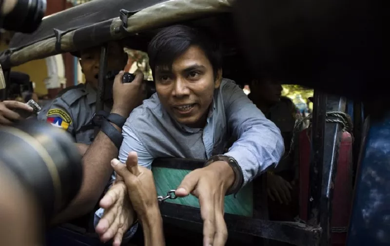 Reuters journalist Kyaw Soe Oo (C) talks to the media as he leaves after a court appearance in Yangon on January 10, 2018.
Myanmar police formally filed charges on January 10 against two Reuters reporters accused of breaching the Official Secrets Act, a judge said, an offence that carries up to 14 years in prison. / AFP PHOTO / YE AUNG THU