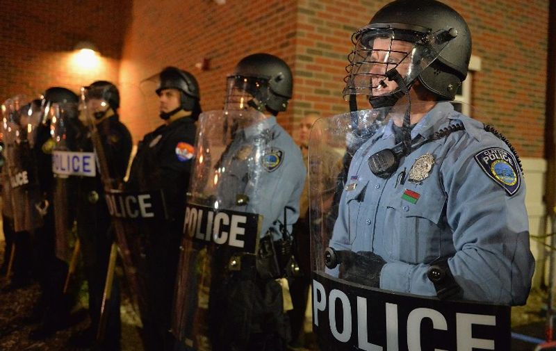 (FILES) This November 19, 2014 file photo shows police officers as they stand in riot gear during a protest outside the Ferguson Police Department in Ferguson, Missouri.  It is an image both shocking and yet sadly familiar: a black teenager face down in the middle of a residential street in a pool of his own blood. In another time, the police shooting of Michael Brown in Ferguson, Missouri on August 9, 2014 might have just been another local "incident." But those pictures -- of his uncovered body, of the angry faces of his neighbors as they set fire to a convenience store, of the tear gas and riot gear, of stoic protesters standing with their hands raised -- inspired and politicized a new generation of activists. AFP PHOTO / Michael B. Thomas