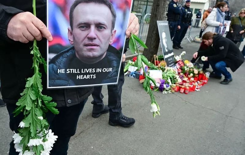 People place flowers and candles at a makeshift memorial for Kremlin critic Alexei Navalny at the Russian embassy in Bucharest, Romania, on February 18, 2024. Alexei Navalny's supporters accused Russian authorities of being "killers" who were "covering their tracks" by refusing to hand over his body, as the Kremlin stayed silent despite Western accusations and a flood of tributes to the late opposition leader. Tributes continued to pour in, as supporters staged anti-Putin protests and pop-up tributes to Navalny around the world. Navalny's death was announced on February 16, 2024 after three years in detention and a poisoning that he blamed on the Kremlin. (Photo by Daniel MIHAILESCU / AFP)