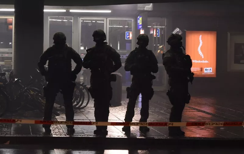 Police officers in riot gear are seen guarding the entrance to the closed central station in Munich on January 1, 2016. 
Germany was on high alert as police hunted for up to seven people suspected of plotting a New Year's Eve suicide attack in Munich in the name of the Islamic State group. / AFP / Christof STACHE / ALTERNATIVE CROP