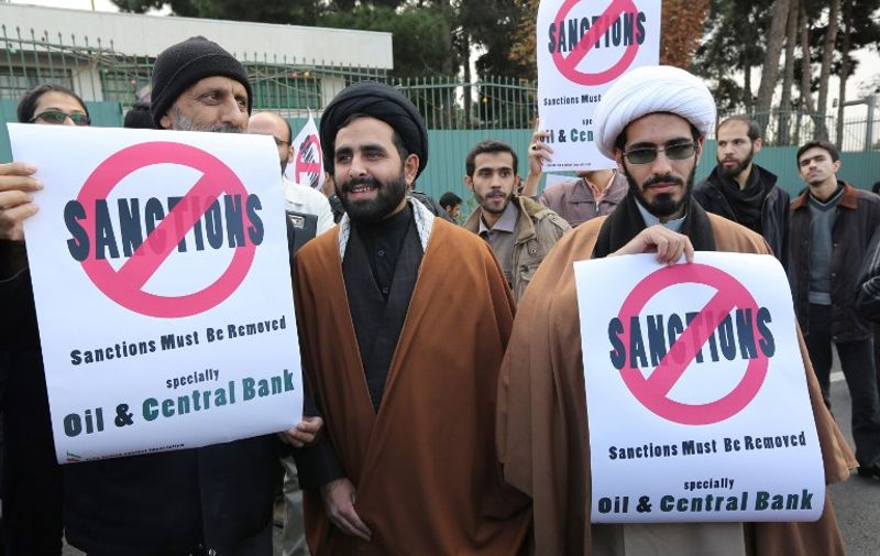Iranian men hold placards during a demonstration outside the Tehran Research Reactor in the capital Tehran on November 23, 2014, to show their support to Iran's nuclear programme. Iran and six world powers are holding talks in Vienna to reach a lasting agreement on Tehran's disputed nuclear programme before November 24. Such a deal, after 12 years of rising tensions, is aimed at easing fears that Tehran will develop nuclear weapons under the guise of its civilian activities -- an ambition the Islamic republic has always fiercly denied. AFP PHOTO/ATTA KENARE / AFP / ATTA KENARE
