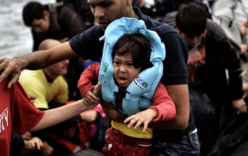 TOPSHOTS
A man carries a child as refugees and migrants arrive on a dinghy to the Greek island of Lesbos after crossing the Aegean sea from Turkey on September 30, 2015. Europe's migrant crisis was set to be in focus at the UN with Secretary General Ban Ki-moon seeking to muster a global response to the exodus of vast numbers of people from Syria and elsewhere. AFP PHOTO / ARIS MESSINIS