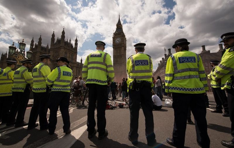 Members of the police look on as demonstrators take part in a protest against the Conservative government's austerity measures in central London on May 30, 2015. 
AFP PHOTO / LEON NEAL