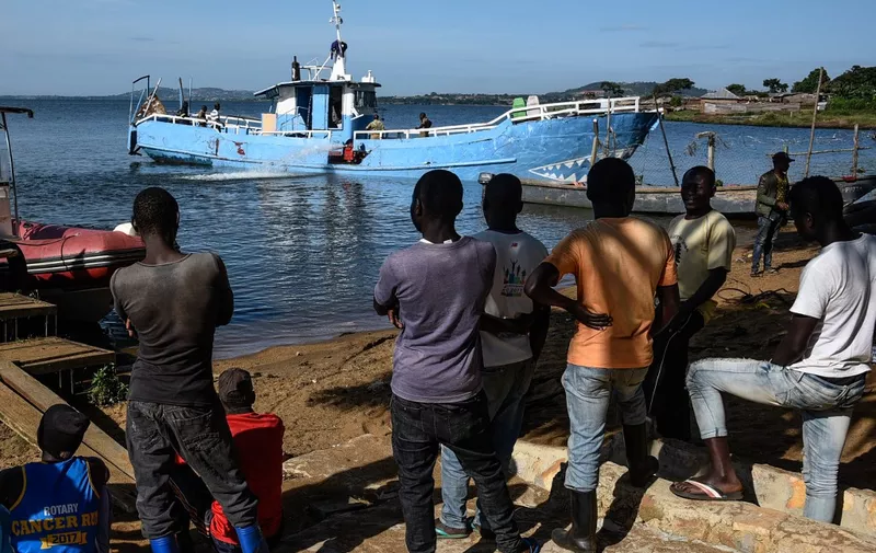 People watch as the MV K-Palm, the cruise boat which capsized and killed at least 32 people, is drained after being alvaged in Lake Victoria near Mutima village, south of Kampala, on November 30, 2018. Most of the victims were young, affluent Ugandans enjoying a raucous end-of-year party, according to a survivor. (Photo by Isaac Kasamani / AFP)