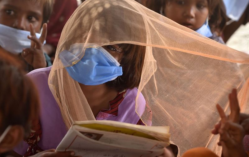 Gypsy children wearing facemasks as a preventive measure against the spread of the COVID-19 coronavirus attend a tuition class at a slum area in Lahore on July 10, 2020. (Photo by Arif ALI / AFP)
