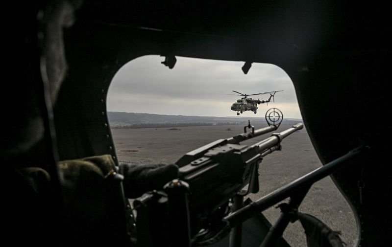 A Ukrainian door gunner watches a second Mil Mi-8 helicopter as he flies in eastern Ukraine on March 10, 2023. (Photo by Aris Messinis / AFP)