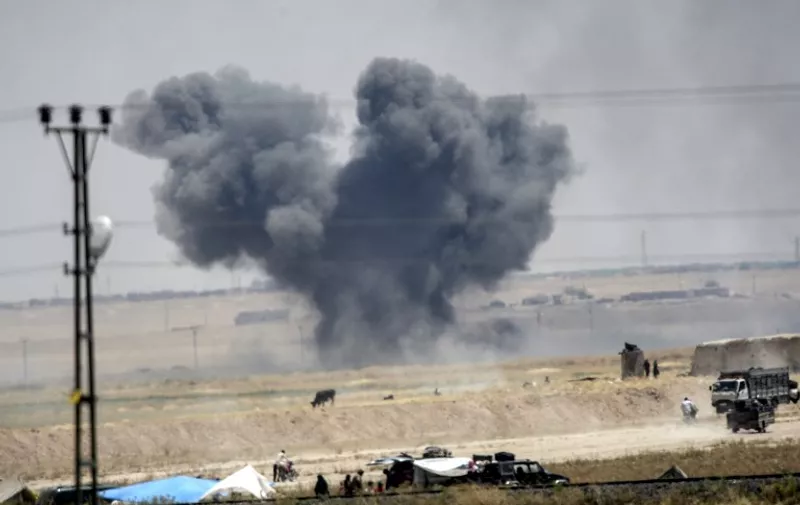 A picture taken from Akcakale, in Turkey shows black smoke billowing into sky after an airstrike during clashes in the eastern part of the Syrian town of Tal Abyad on June 14, 2015. Turkish security forces on June 13 used water cannon and fired warning shots to push Syrians back from the frontier as thousands massed at a border crossing to escape escalating fighting, an AFP photographer said. The Syrians were being held behind barbed wire fences around the Turkish crossing of Akcakale in the southeast of the country. They are fleeing a looming battle as Kurdish forces advance on the Syrian town of Tal Abyad, which is held by Islamic State (IS) jihadists and lies just across the Turkish border. AFP PHOTO / BULENT KILIC