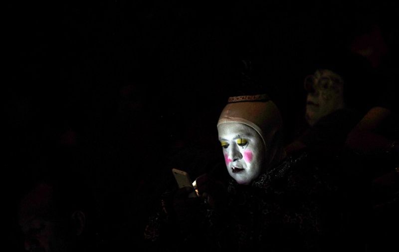 A clown looks at his phone during the second day of the XXI Convention of Clowns, at the Jimenez Rueda Theatre, in Mexico City on October 18, 2016. 
Latin American clowns hold their 21st annual conference in Mexico City from October 17 through 20. The lurking clown phenomenon as a wave of hysteria about sightings of "creepy" or "killer" clowns that sweeps the United States and European nations will be discussed. / AFP PHOTO / PEDRO PARDO