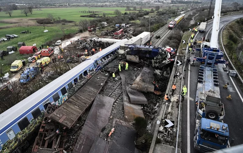 TOPSHOT - Police and emergency crews examine the debris of a crushed wagon on the second day after a train accident in the Tempi Valley near Larissa, Greece, March 2, 2023. - At least 46 people were killed and another 85 injured after a collision between two trains caused a derailment near the Greek city of Larissa late at night on February 28, 2023, authorities said. A fire services spokesman confirmed that three carriages skipped the tracks just before midnight after the trains -- one for freight and the other carrying 350 passengers - collided about halfway along the route between Athens and Thessaloniki. (Photo by Sakis MITROLIDIS / AFP)
