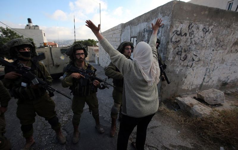 A Palestinian woman shouts at Israeli soldiers in the village of Kafr Malik, northeast of Ramallah on June 14, 2015, after clashes that resulted in the death of 21-year-old Palestinian Abdallah Ghanayem. An army spokesman told AFP that the Palestinian had died after he threw an incendiary device at a jeep and the vehicle overturned on him. Palestinian security sources said, Israeli soldiers killed Ghanayem by hitting him with their jeep during clashes near Ramallah in the occupied West Bank. AFP PHOTO / ABBAS MOMANI