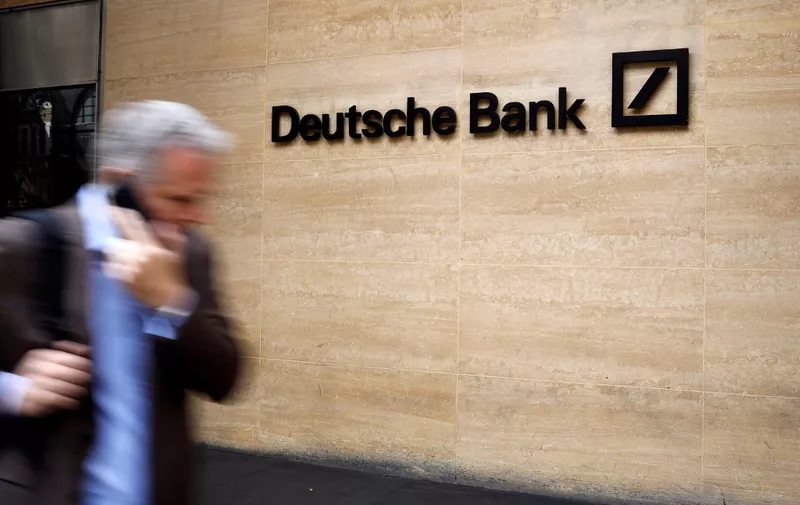 A pedestrian walks past a logo outside the offices of German bank Deutsche Bank in central London on July 8, 2019. - Germany's biggest lender Deutsche Bank said Sunday it would cut 18,000 jobs by 2022, as the former leading light of the country's financial sector looks to escape years of turmoil. With almost 8,000 staff, Deutsche Bank is one of the biggest employers in the City of London. (Photo by Tolga Akmen / AFP)