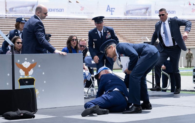 US President Joe Biden is helped up after falling during the graduation ceremony at the United States Air Force Academy, just north of Colorado Springs in El Paso County, Colorado, on June 1, 2023. (Photo by Brendan Smialowski / AFP)