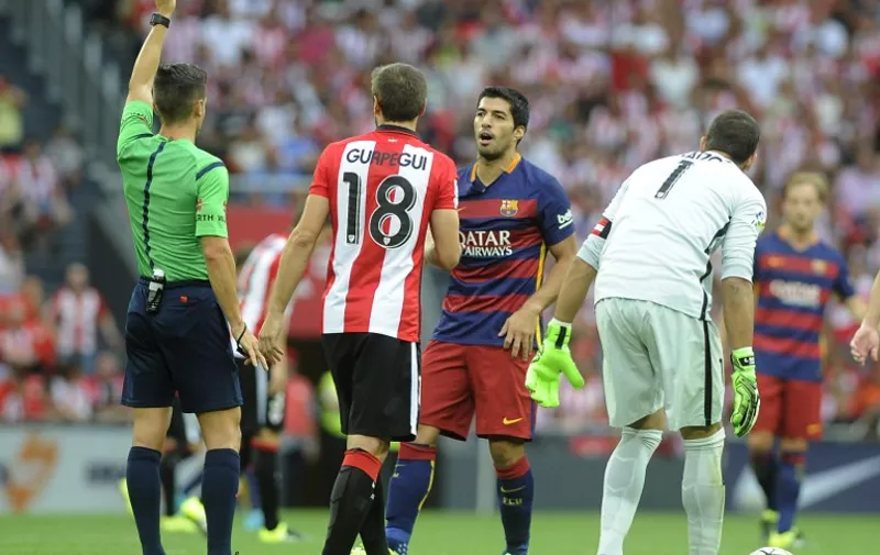 Referee shows a yellow card to Barcelona's Uruguayan forward Luis Suarez (2ndR) during the Spanish league football match Athletic Club Bilbao vs FC Barcelona at the San Mames stadium in Bilbao on August 23, 2015.  AFP PHOTO/ ANDER GILLENEA