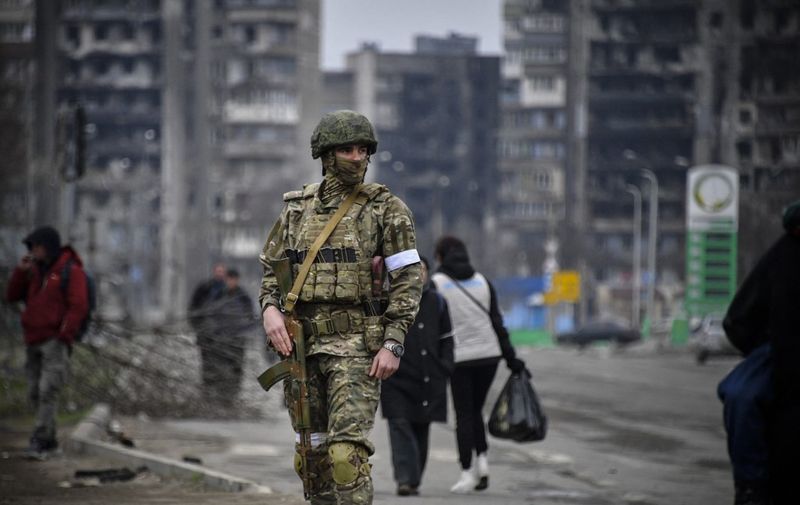 A Russian soldier patrols in a street of Mariupol on April 12, 2022, as Russian troops intensify a campaign to take the strategic port city, part of an anticipated massive onslaught across eastern Ukraine, while Russia's President makes a defiant case for the war on Russia's neighbour. - *EDITOR'S NOTE: This picture was taken during a trip organized by the Russian military.* (Photo by Alexander NEMENOV / AFP)