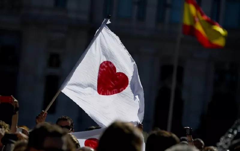 A woman holds a white flag with a red heart during a demonstration called by the "Let's talk" (Parlem,Hablemos) association for dialogue in Catalonia in October 07, 2017 at Cibeles square in Madrid.
Spain braced for more protests despite tentative signs that the sides may be seeking to defuse the crisis after Madrid offered a first apology to Catalans injured by police during their outlawed independence vote. / AFP PHOTO / GABRIEL BOUYS