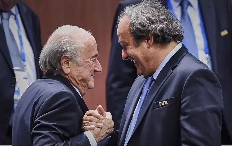 FIFA President Sepp Blatter (Foreground-L) shakes hands with UEFA president Michel Platini after being re-elected following a vote to decide on the FIFA presidency in Zurich on May 29, 2015. Sepp Blatter won the FIFA presidency for a fifth time after his challenger Prince Ali bin al Hussein withdrew just before a scheduled second round. AFP PHOTO / MICHAEL BUHOLZER / AFP / MICHAEL BUHOLZER