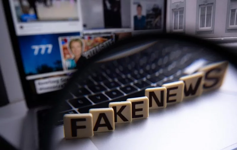 This illustration photograph shows letters reading "fake news" seen through a magnifying glass, against a laptop screen displaying other illustration images of various alleged fake news, disinformation campaigns or conspiracy theories, in Mulhouse, eastern France, on December 1, 2023 . (Photo by SEBASTIEN BOZON / AFP)
