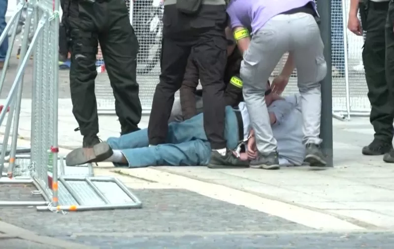 This image taken from video footage obtained by AFPTV shows security personnel apprehending a suspected gunman (C/GROUND) after Slovakia's Prime Minister was shot in Handlova on May 15, 2024. Slovakia's Prime Minister Robert Fico was battling life-threatening wounds after officials said he was shot multiple times in an assassination attempt condemned by European leaders. (Photo by RTVS / AFP)